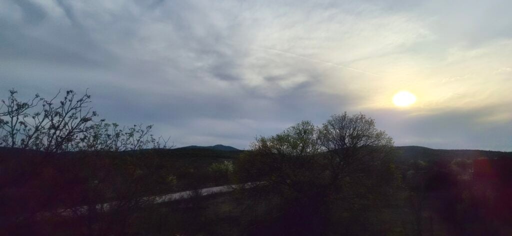 Detaljan pogled na zelena brda s drvećem pod dramatičnim oblačnim nebom, snimljeno s Galaxy S26 kamerom.