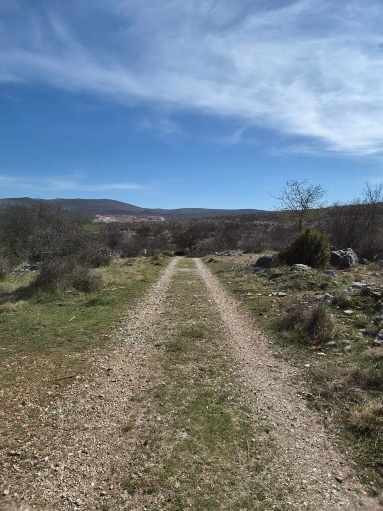 Pejzaž krškog kraja sa suhom travom u prvom planu i makadamskim putem, test Galaxy S26 pejzaža.