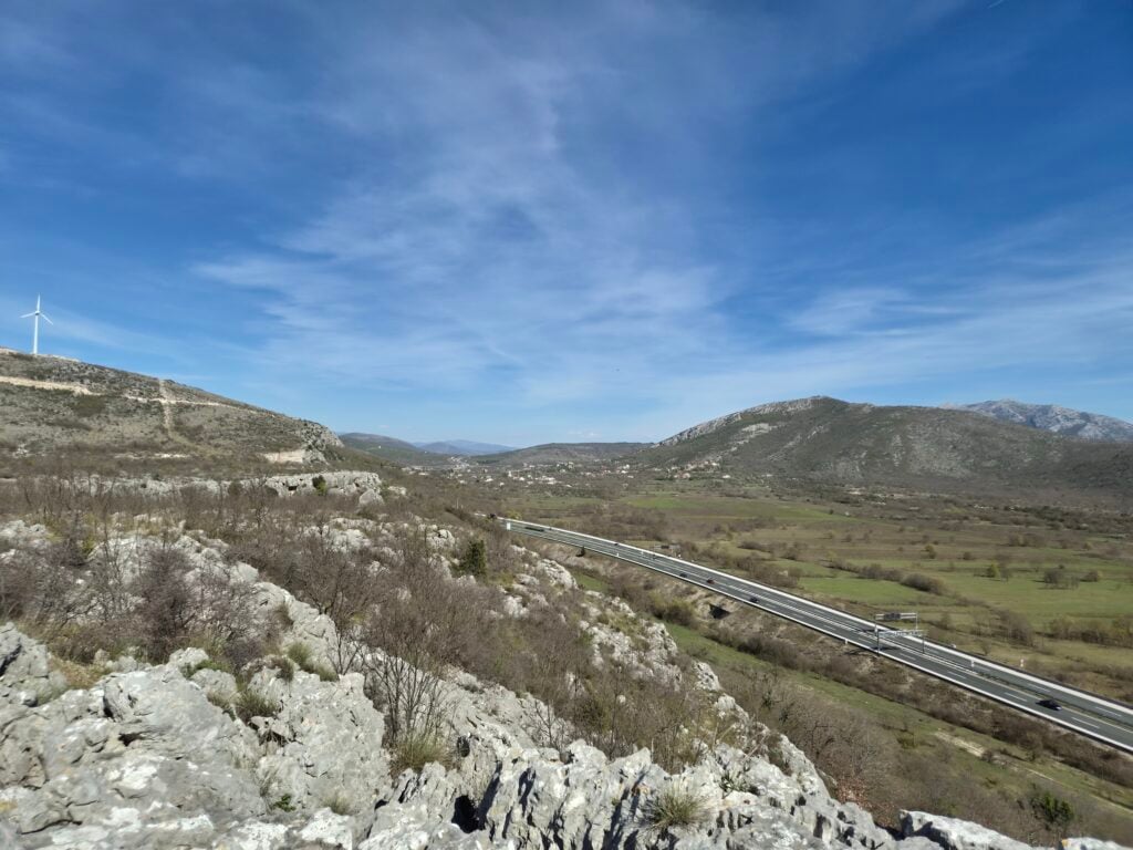 Široki pogled na dolinu s krškim brdima kroz koju prolazi autocesta s više traka, snimljeno Samsung Galaxy S26 kamerom.